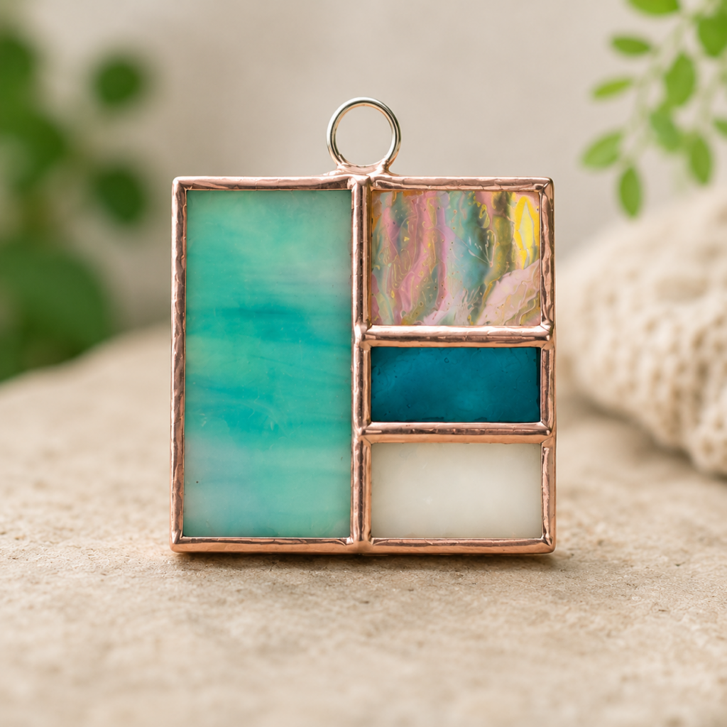 Handcrafted stained glass pendant featuring turquoise, blue, and iridescent glass in a copper frame