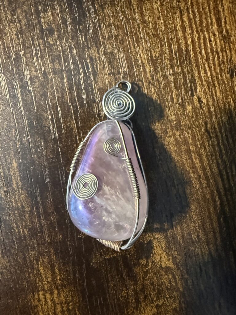 Handmade wire-wrapped purple stone pendant featuring decorative silver-tone spiral wirework.