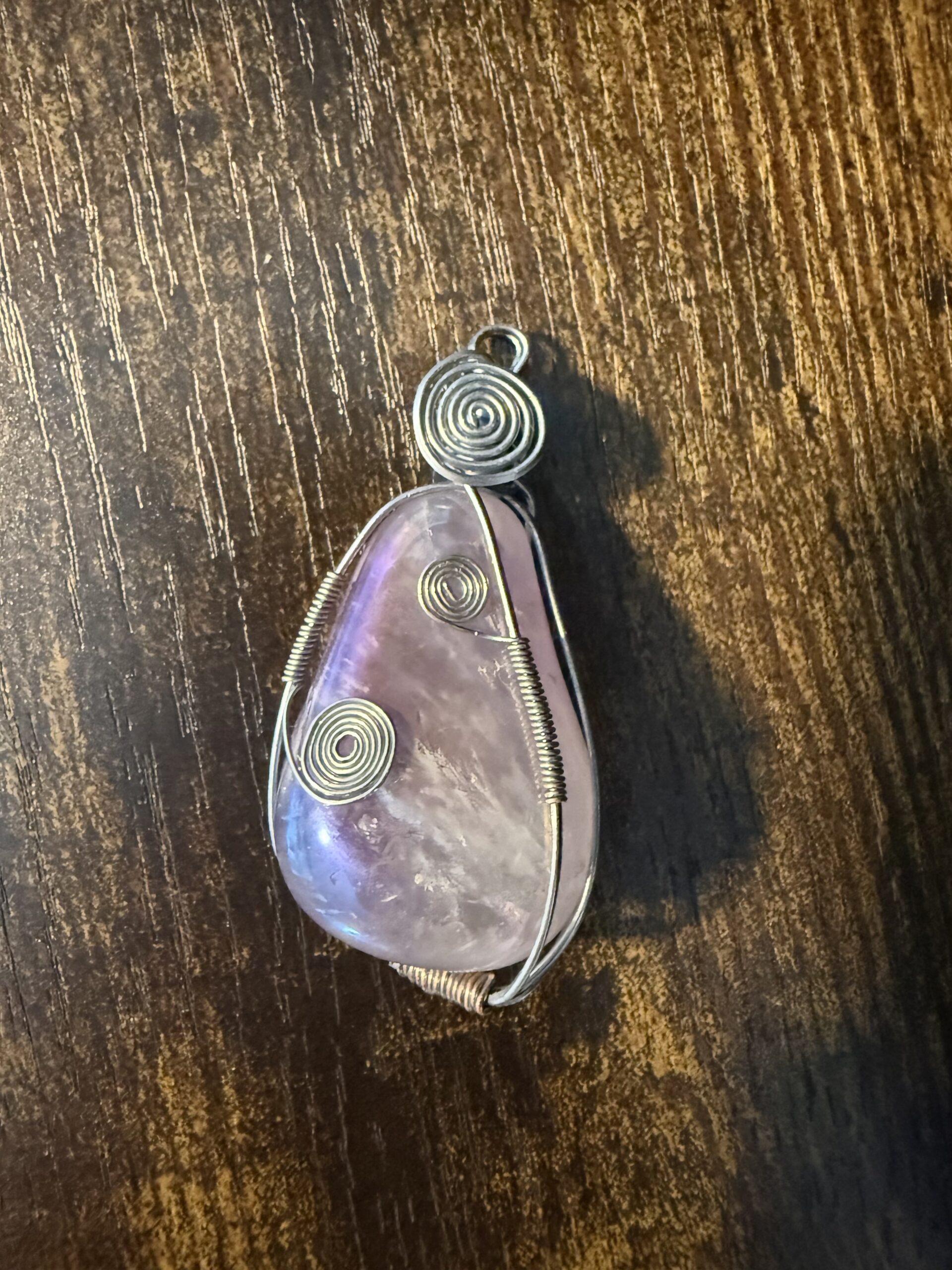 Handmade wire-wrapped purple stone pendant featuring decorative silver-tone spiral wirework.