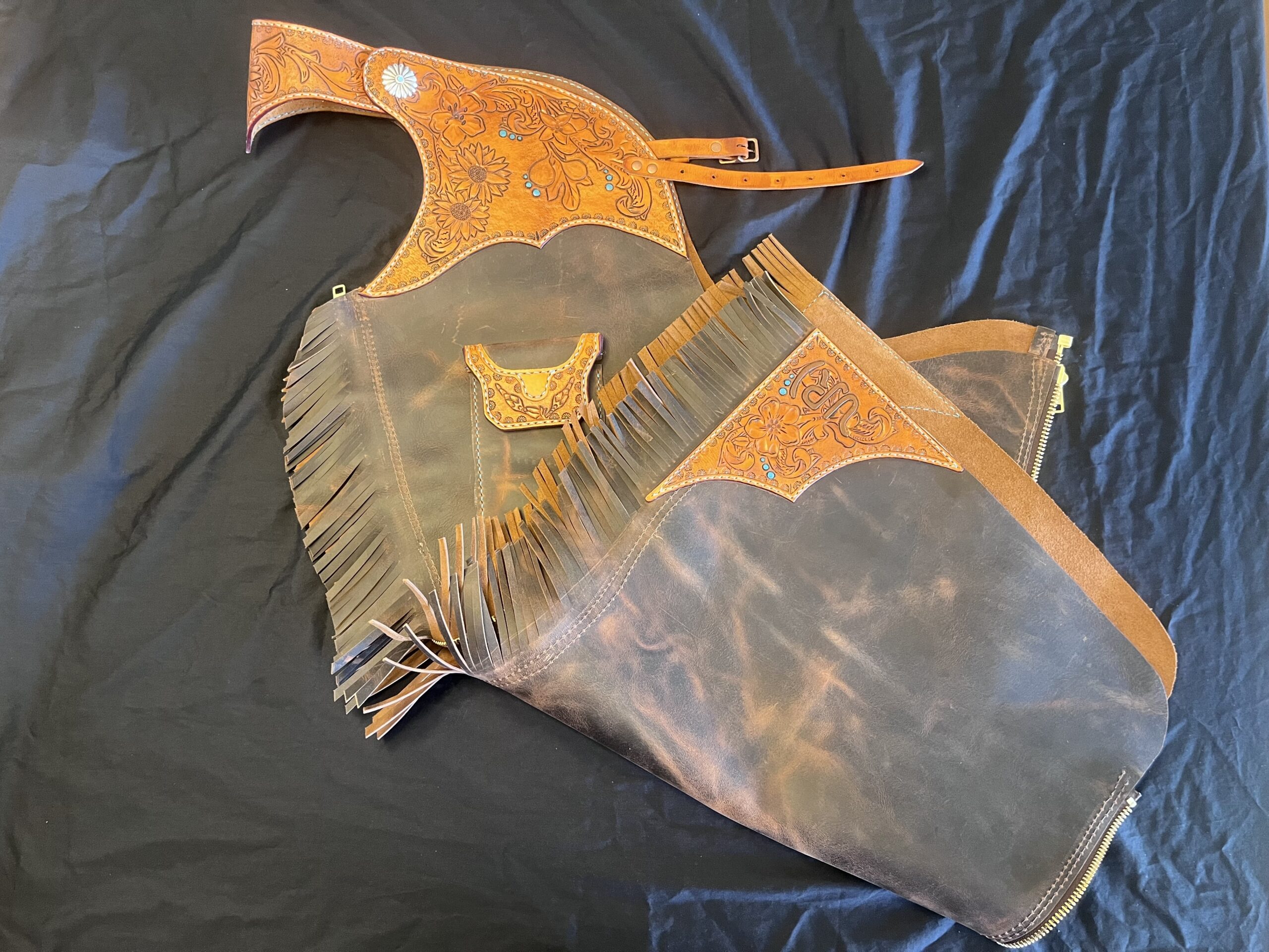 Handcrafted leather chinks with fringe and decorative floral tooling created for the Rocky Mountain Folk School custom chaps and chinks workshop.