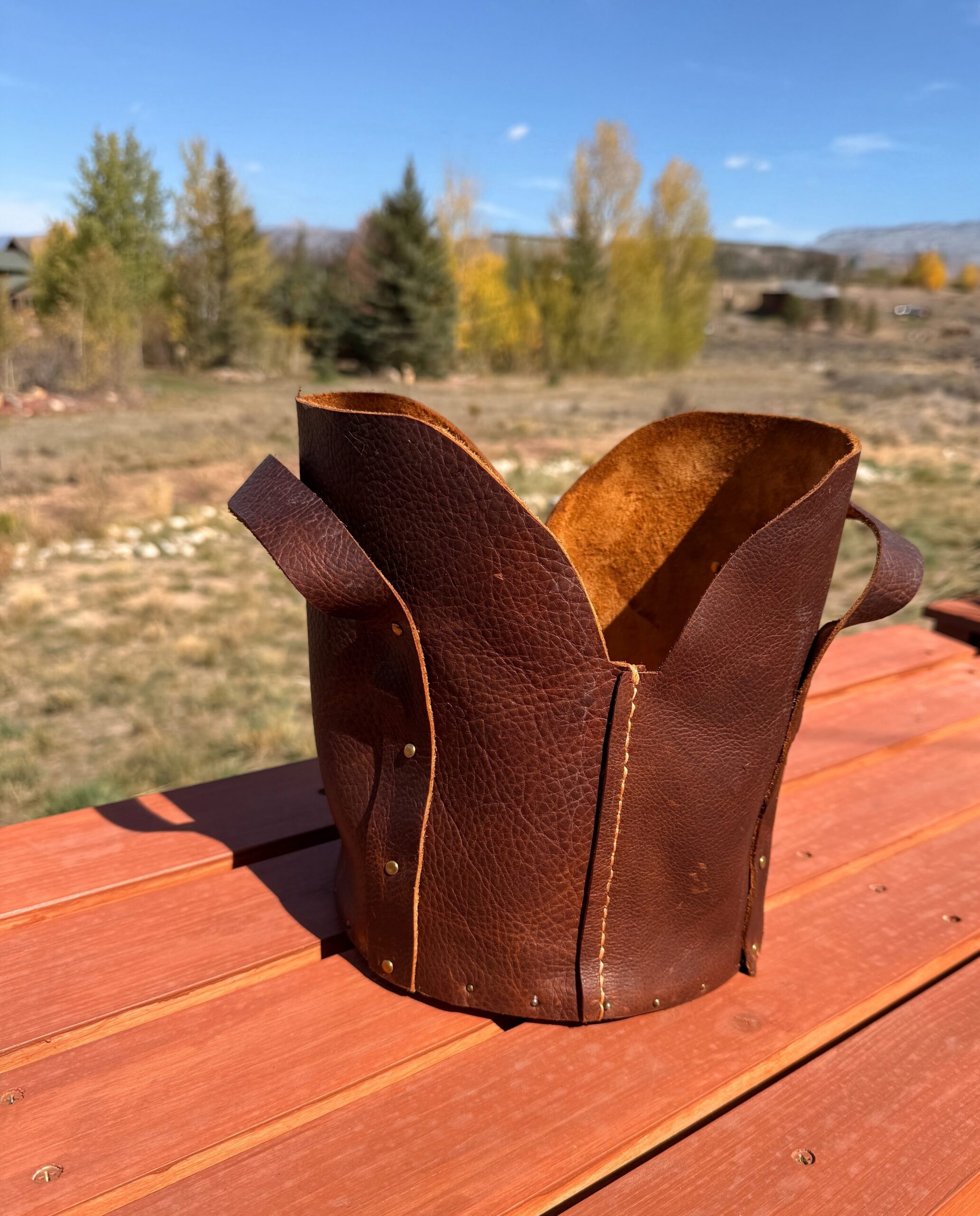 Handmade brown leather handle bag with decorative stitching and rivets, showcasing a leatherworking workshop at Rocky Mountain Folk School in Grand Lake, Colorado.